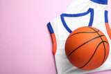 Basketball uniform and ball on pink background, top view. Space for text