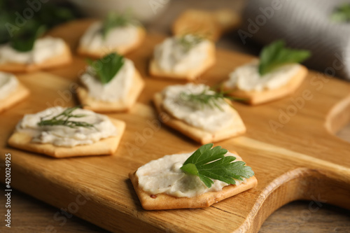 Delicious crackers with humus, parsley and dill on wooden table, closeup