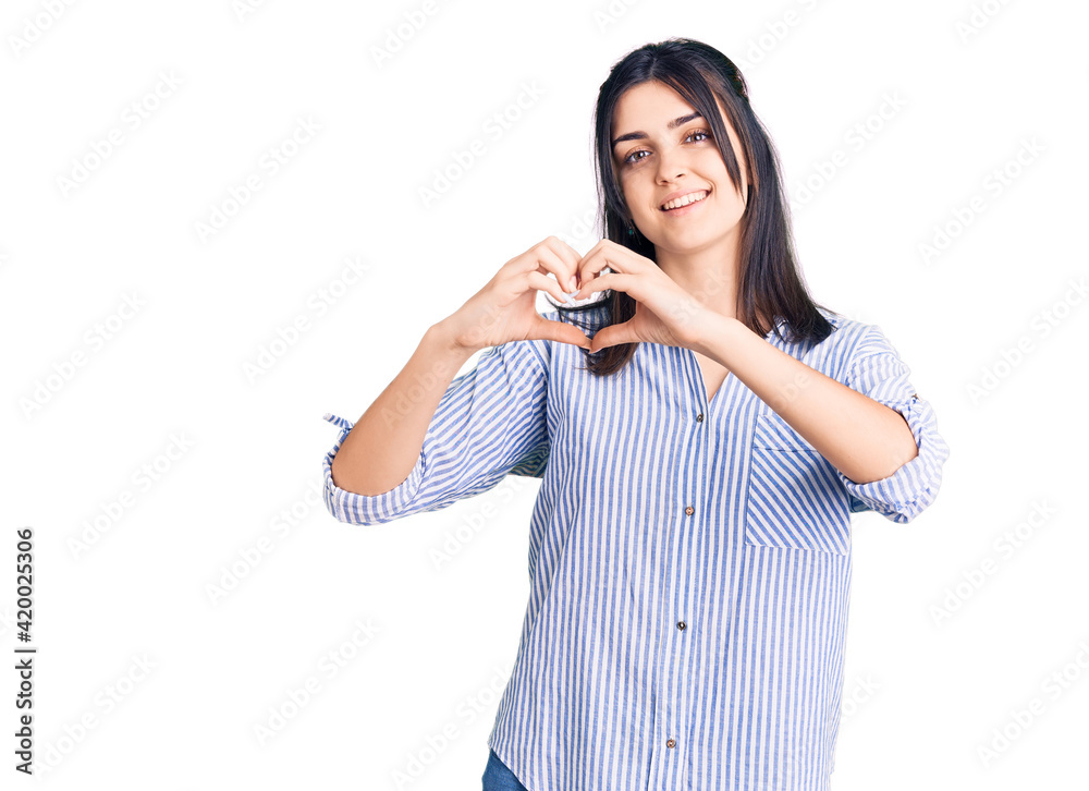 Young beautiful girl wearing striped shirt smiling in love showing heart symbol and shape with hands. romantic concept. Young beautiful girl wearing striped shirt smiling in love showing heart symbol and shape with hands. romantic concept.