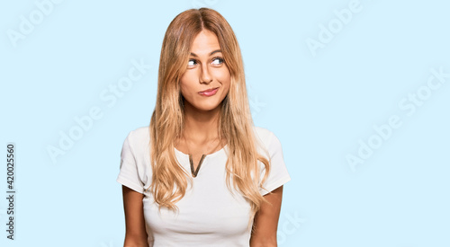 Photos Beautiful blonde young woman wearing casual white tshirt smiling looking to the side and staring away thinking