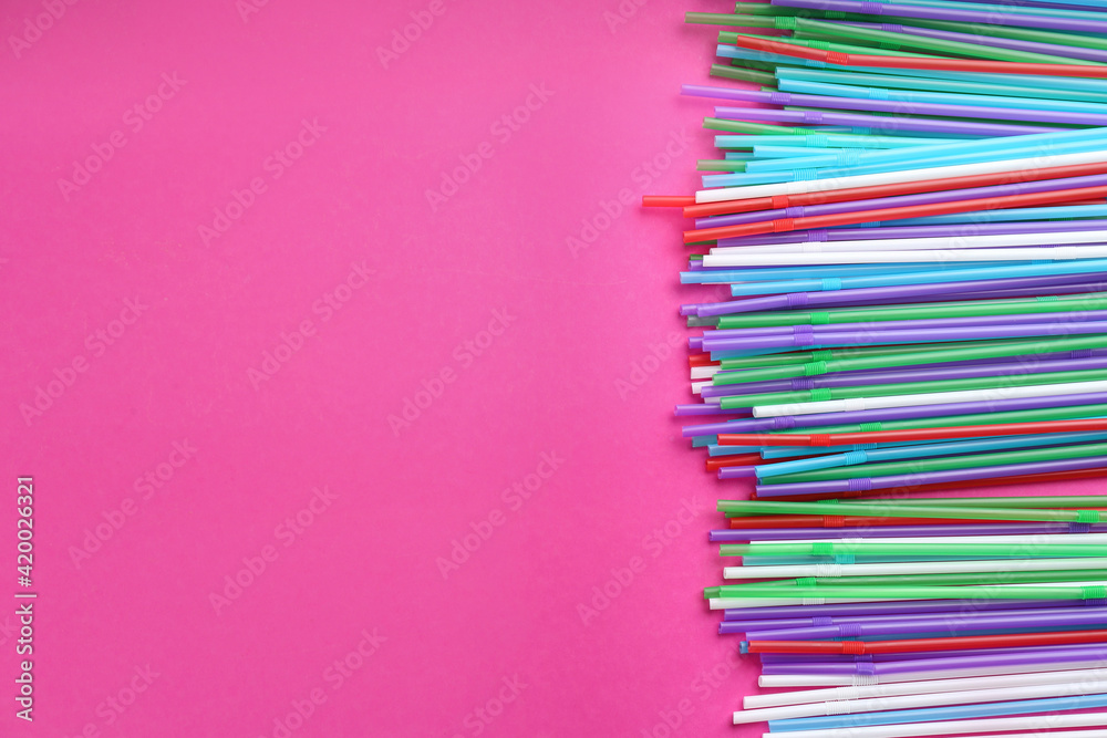 Fototapeta premium Colorful plastic drinking straws on pink background, flat lay. Space for text