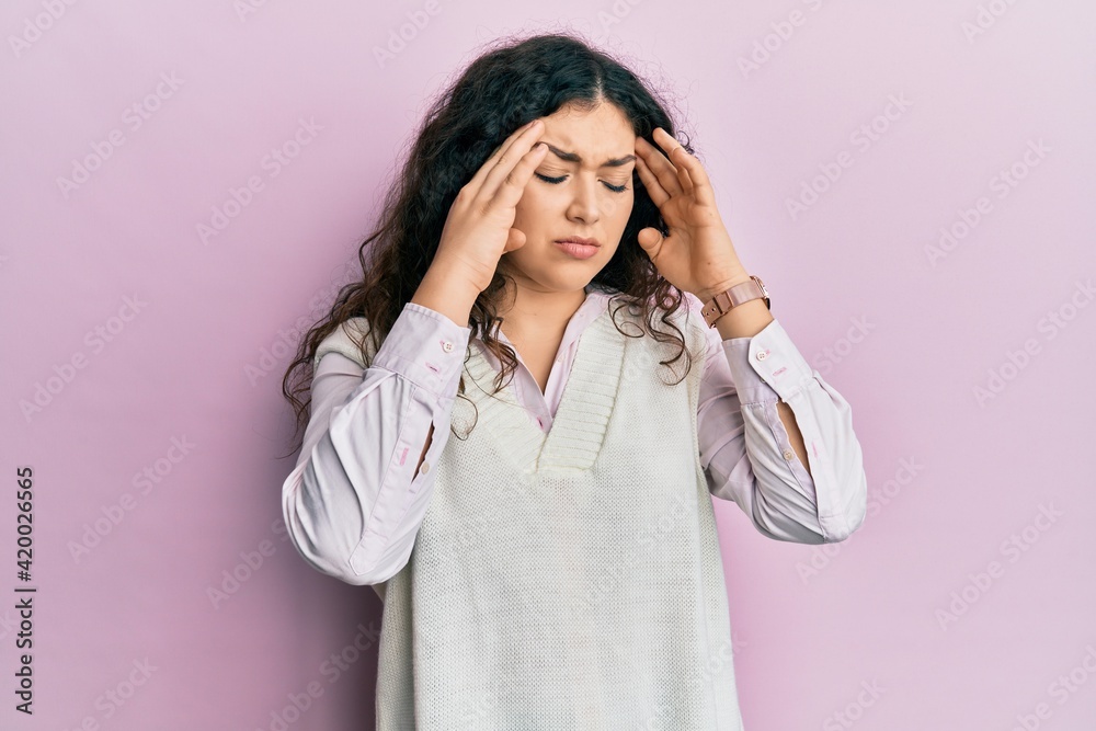 Young brunette woman with curly hair wearing casual clothes with hand on head, headache because stress. suffering migraine. Young brunette woman with curly hair wearing casual clothes with hand on head, headache because stress. suffering migraine.