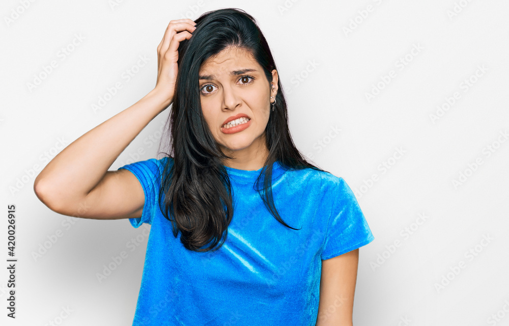 Young hispanic woman wearing casual clothes confuse and wonder about question. uncertain with doubt, thinking with hand on head. pensive concept. Young hispanic woman wearing casual clothes confuse and wonder about question. uncertain with doubt, thinking with hand on head. pensive concept.