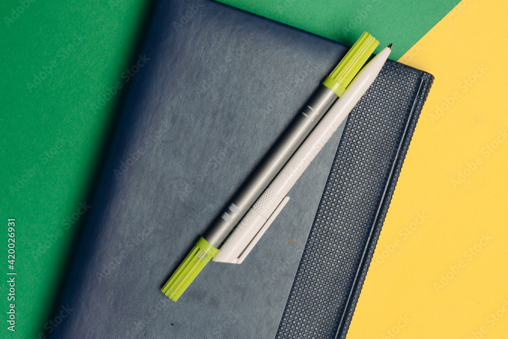 notepad with markers and pens on yellow green background and office supplies codespace notepad with markers and pens on yellow green background and office supplies codespace
