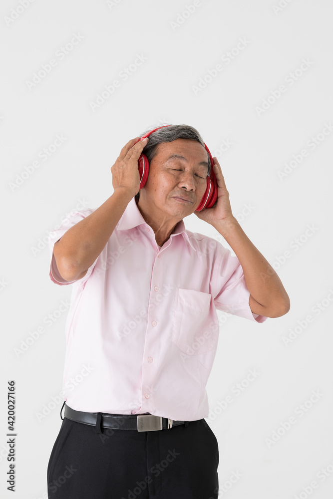 Portrait of a good-looking full of energy and active senior older Asian man holding and wearing red headphone and listening to music with joyfully and happy face and deep emotion on white background. Portrait of a good-looking full of energy and active senior older Asian man holding and wearing red headphone and listening to music with joyfully and happy face and deep emotion on white background.