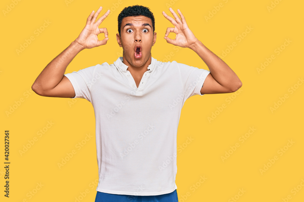 Fototapeta premium Young arab man wearing casual clothes looking surprised and shocked doing ok approval symbol with fingers. crazy expression