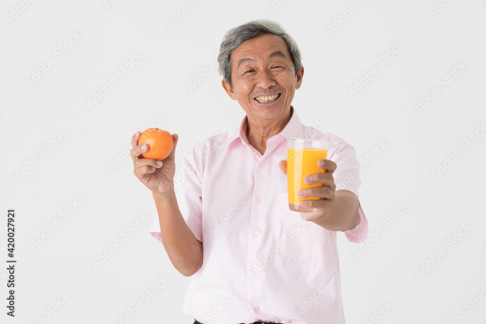 Kindly face good looking senior old Asian man with gray hair holding glass of orange juice and apple with happiness and self-confidence. Healthcare and wellness concept