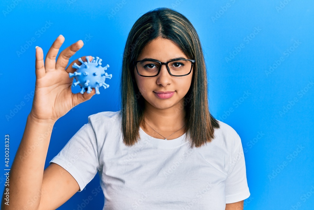 Young latin woman holding virus toy thinking attitude and sober expression looking self confident Young latin woman holding virus toy thinking attitude and sober expression looking self confident
