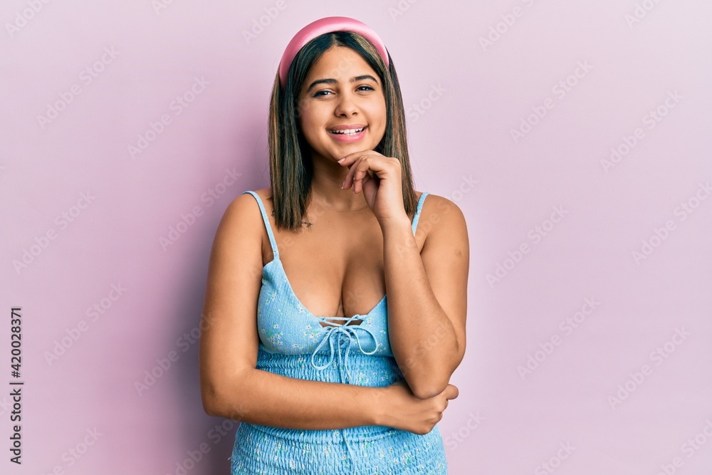 Young latin woman wearing summer clothes looking confident at the camera with smile with crossed arms and hand raised on chin. thinking positive. Young latin woman wearing summer clothes looking confident at the camera with smile with crossed arms and hand raised on chin. thinking positive.