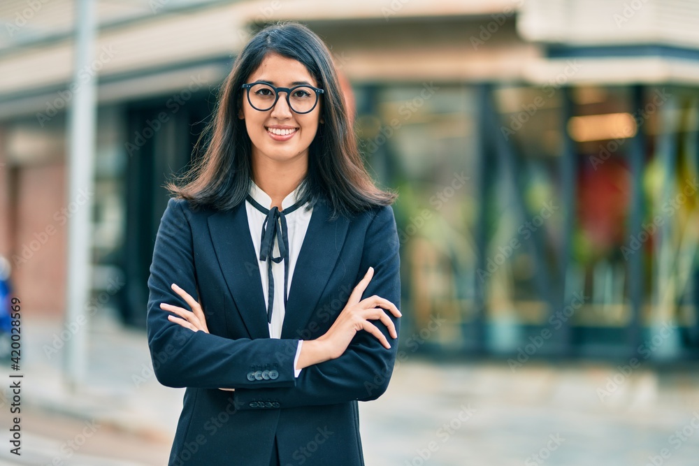 Fototapeta premium Young hispanic businesswoman smiling happy standing at the city.