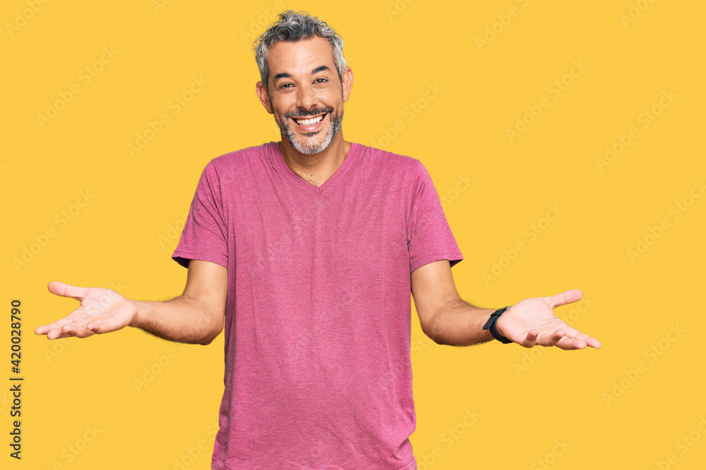 Middle age grey-haired man wearing casual clothes smiling cheerful offering hands giving assistance and acceptance. Middle age grey-haired man wearing casual clothes smiling cheerful offering hands giving assistance and acceptance.