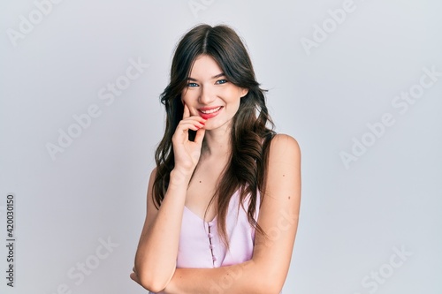 Young beautiful caucasian girl wearing casual clothes smiling looking confident at the camera with crossed arms and hand on chin. thinking positive.