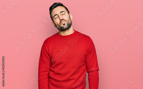 Young hispanic man wearing casual clothes looking at the camera blowing a kiss on air being lovely and sexy. love expression.