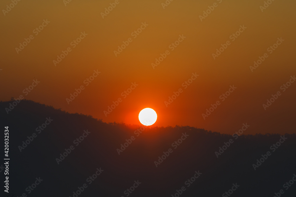 Sunrise over mountains and forest  with sky and sunbeams.
