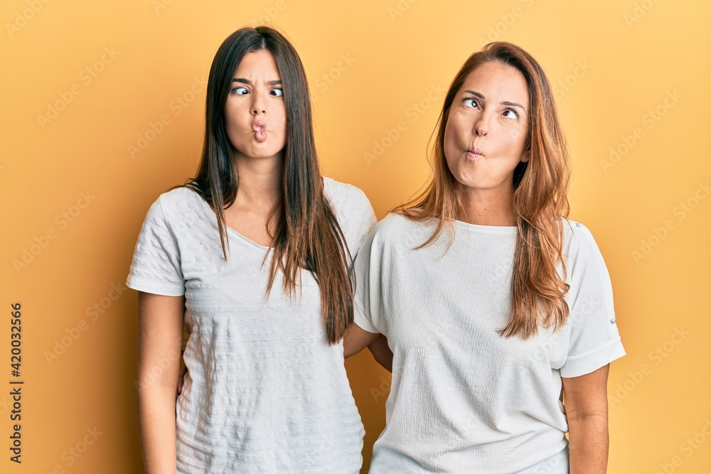 Hispanic family of mother and daughter wearing casual white tshirt making fish face with lips, crazy and comical gesture. funny expression. Hispanic family of mother and daughter wearing casual white tshirt making fish face with lips, crazy and comical gesture. funny expression.