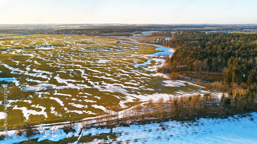 Season change. March rural landscape. Winter crops and plowed field panorama.