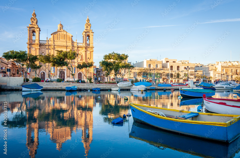 a small boat in a harbor next to a body of water in front of a maltese church in malta