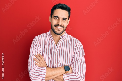 Young hispanic man wearing business shirt happy face smiling with crossed arms looking at the camera. positive person.