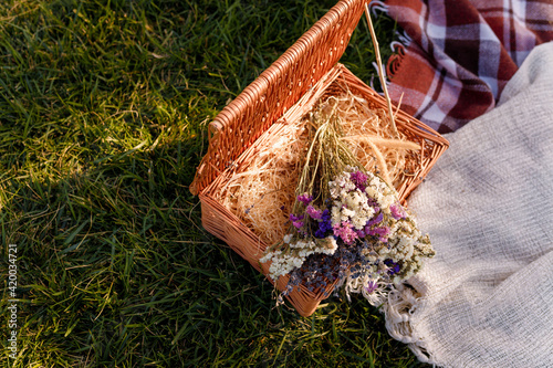 Natural fabric plaids and basket of dry flowers for outdoors picnic, decorative elements, birthday, hygge. photo