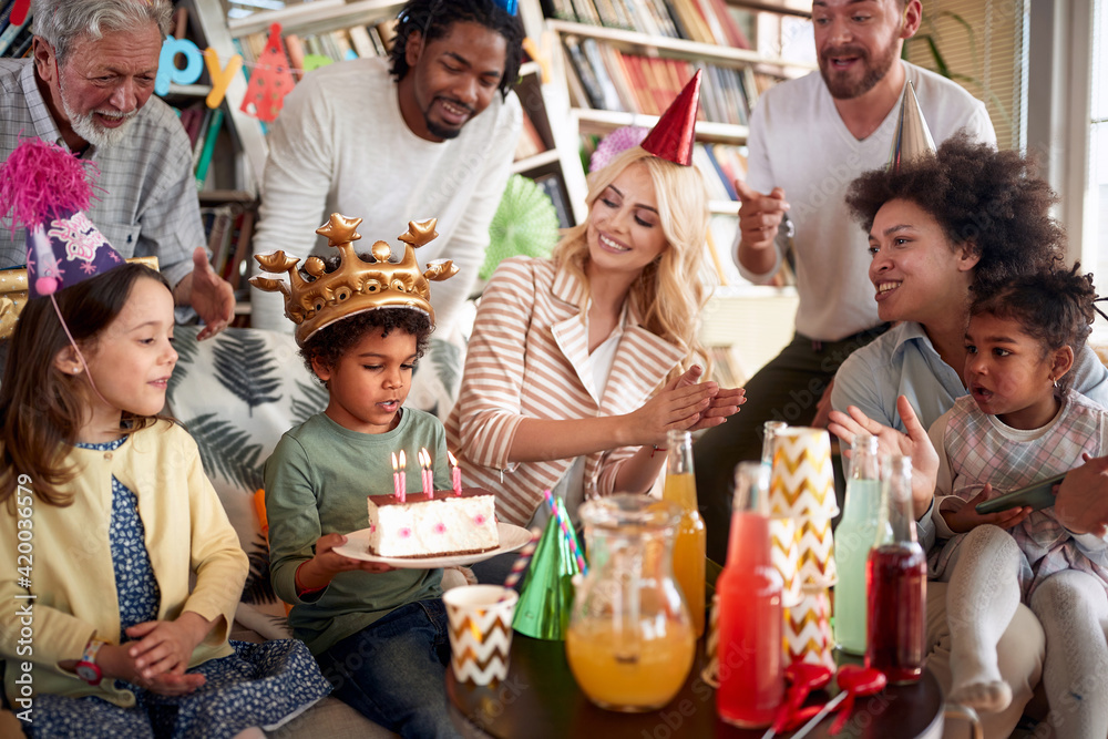 Family and friends singing a birthday song to a little celebrant at his birthday party at home. Family, celebration, together Family and friends singing a birthday song to a little celebrant at his birthday party at home. Family, celebration, together