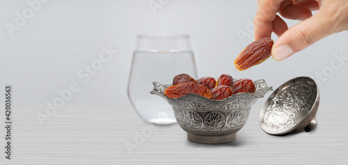 Typical of the month of Ramadan for muslims is the setting here, after the fast has been broken - water and pitted dates. Traditional iftar food. metal bowl full of date fruits symbolizing Ramadan