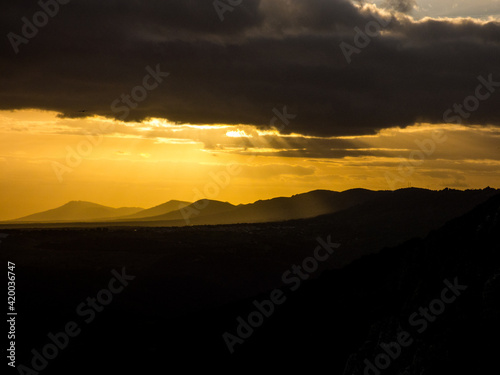 Imagen que destaca el fuerte contraste entre las nubes y el suelo en oscuridad, y una franja central del cielo a la que llegan los últimos rayos del sol al anochecer en el Parque Nacional de Monfragüe