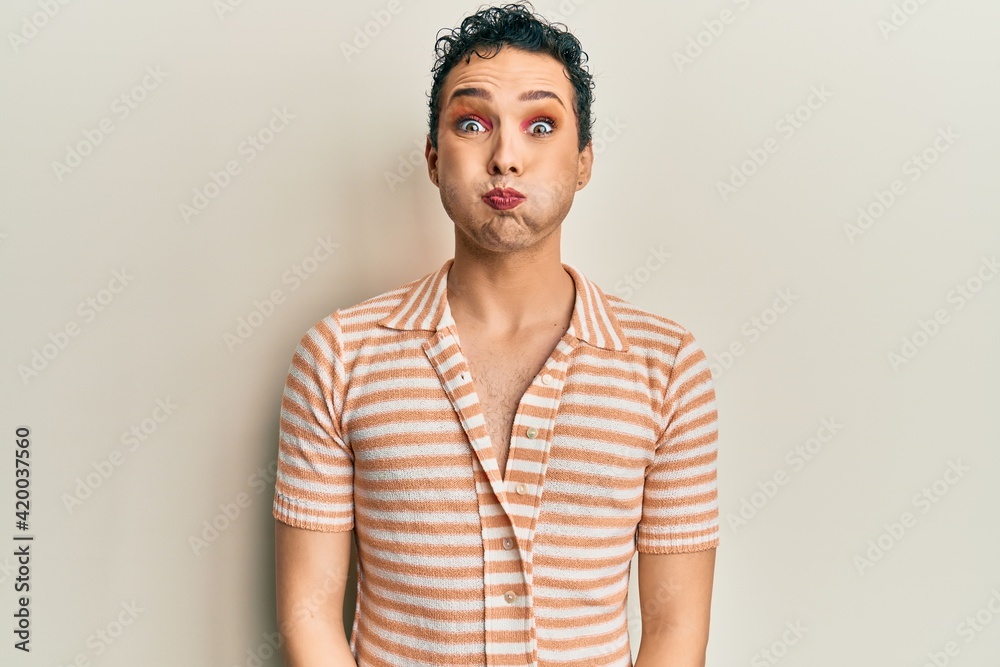 Obraz premium Handsome man wearing make up wearing casual t shirt puffing cheeks with funny face. mouth inflated with air, crazy expression.