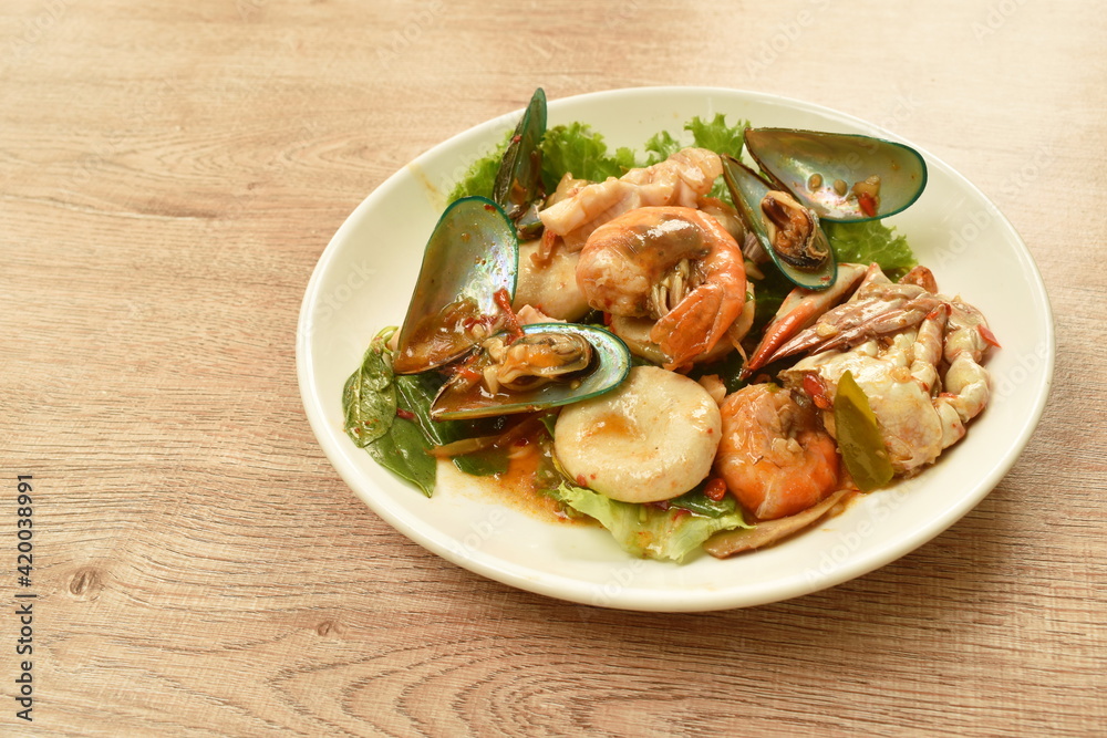 spicy chili fried squid with shrimp couple crab and fresh pepper topping basil leaf on plate spicy chili fried squid with shrimp couple crab and fresh pepper topping basil leaf on plate