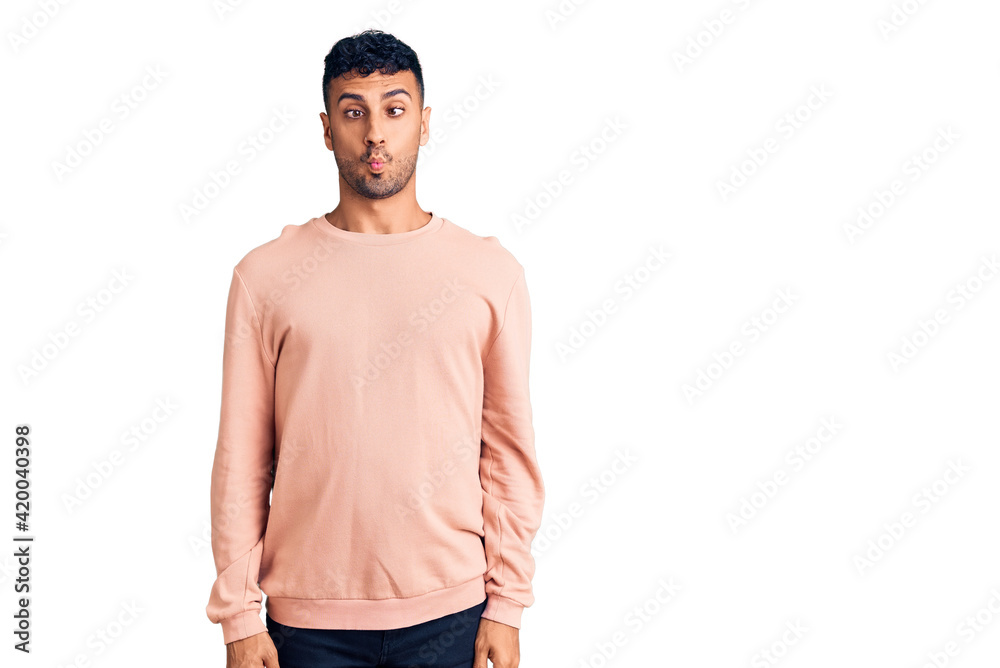 Fototapeta premium Young hispanic man wearing casual clothes making fish face with lips, crazy and comical gesture. funny expression.