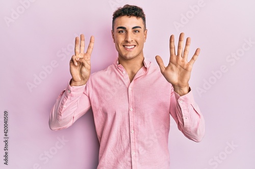 Hispanic young man wearing casual clothes showing and pointing up with fingers number eight while smiling confident and happy.