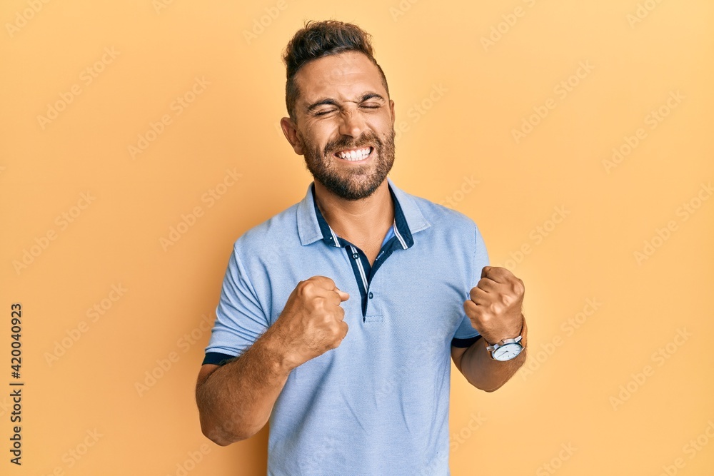 Handsome man with beard wearing casual clothes excited for success with arms raised and eyes closed celebrating victory smiling. winner concept.