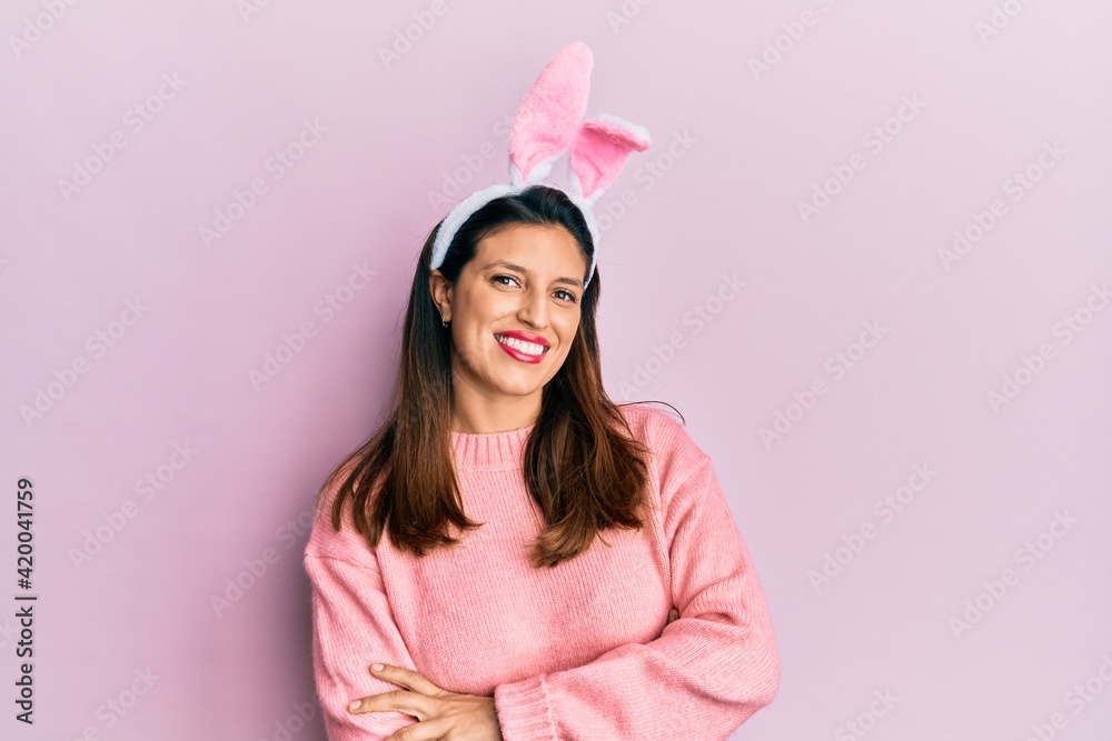 Beautiful hispanic woman wearing cute easter bunny ears happy face smiling with crossed arms looking at the camera. positive person.