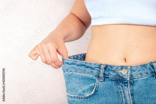 Young woman showing successful weight loss with her jeans on isolate background., Healthcare, Diet concept