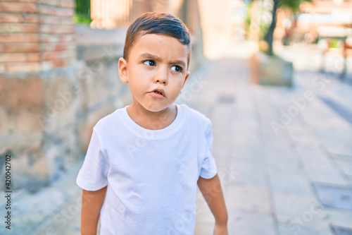 Adorable hispanic boy with angry expression standing at the city.