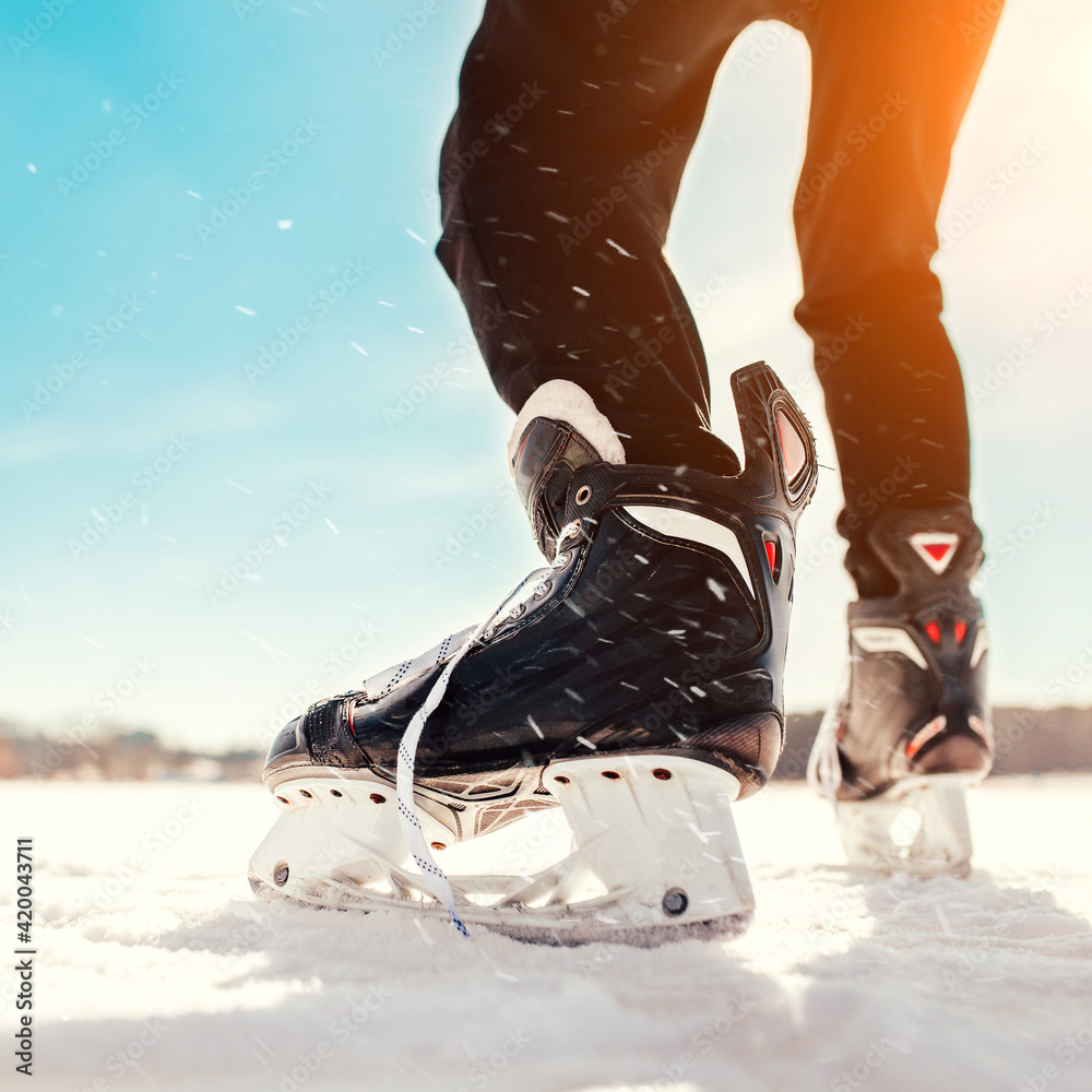 Φωτογραφία A man accelerates on the ice of a lake in ice hockey skates - a sunny day in Can