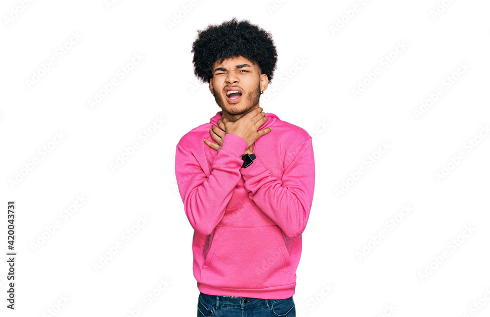 Young african american man with afro hair wearing casual pink sweatshirt shouting suffocate because painful strangle. health problem. asphyxiate and suicide concept. Young african american man with afro hair wearing casual pink sweatshirt shouting suffocate because painful strangle. health problem. asphyxiate and suicide concept.