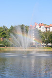 Fountain on lake with rainbow in splashes of water. Selective focus, blur