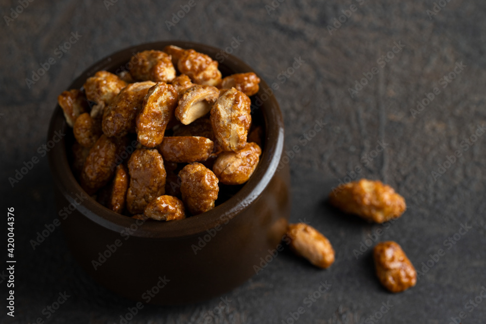 Caramelized Candied Peanuts in ceramic bowl on concrete background. Homemade simple sweet snack. Caramelized Candied Peanuts in ceramic bowl on concrete background. Homemade simple sweet snack.