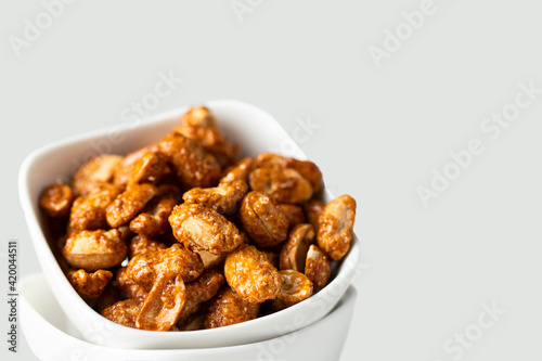 Close up of Caramelized Candied Peanuts in white bowl on concrete background.