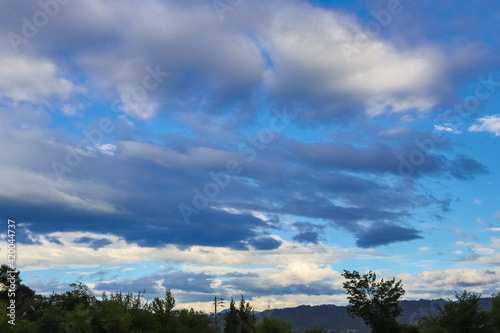 Blue sky approaching dusk, big thick clouds, and mountains.