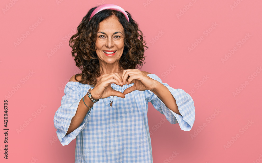 Middle age hispanic woman wearing casual clothes smiling in love showing heart symbol and shape with hands. romantic concept. Middle age hispanic woman wearing casual clothes smiling in love showing heart symbol and shape with hands. romantic concept.