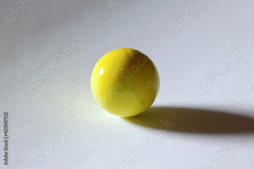 Yellow coloured marble casting a dark shadow