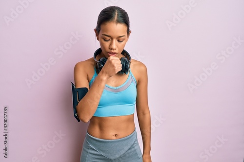 Beautiful hispanic woman wearing sportswear and headphones feeling unwell and coughing as symptom for cold or bronchitis. health care concept. © Krakenimages.com