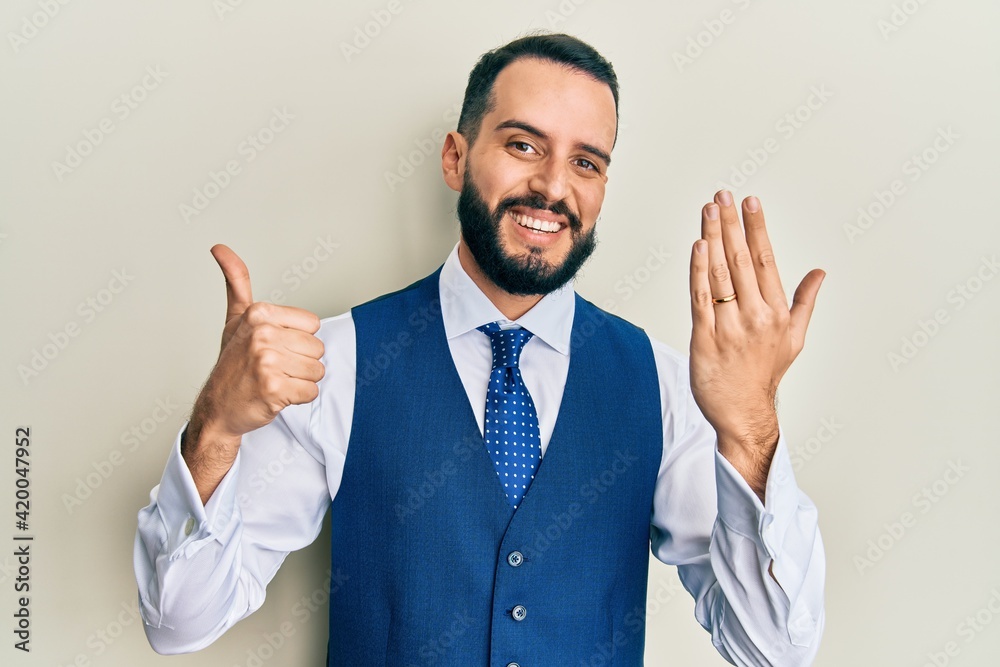 Young man with beard wearing engagement ring smiling happy and positive, thumb up doing excellent and approval sign Young man with beard wearing engagement ring smiling happy and positive, thumb up doing excellent and approval sign