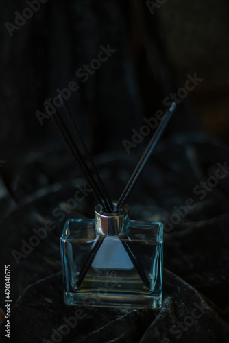 Air freshener in a bottle on a black background. Aroma glass bottle and perfume sticks on black background with selective focus Copy space for text.
