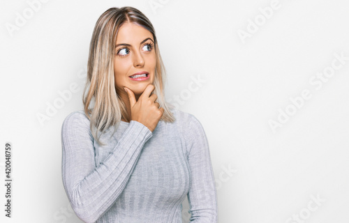Beautiful blonde woman wearing casual clothes thinking worried about a question, concerned and nervous with hand on chin