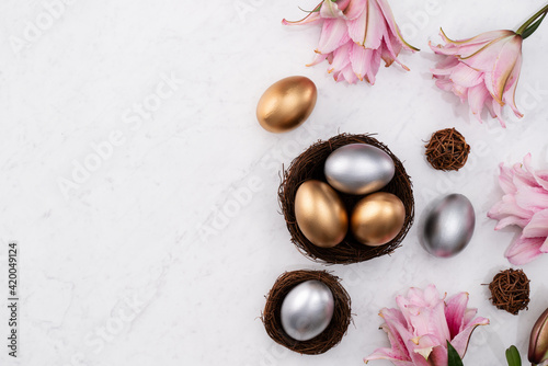 Golden and silver Easter eggs in the nest with pink Double Lily flower.