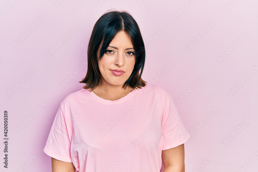 Young hispanic woman wearing casual pink t shirt skeptic and nervous, frowning upset because of problem. negative person. Young hispanic woman wearing casual pink t shirt skeptic and nervous, frowning upset because of problem. negative person.