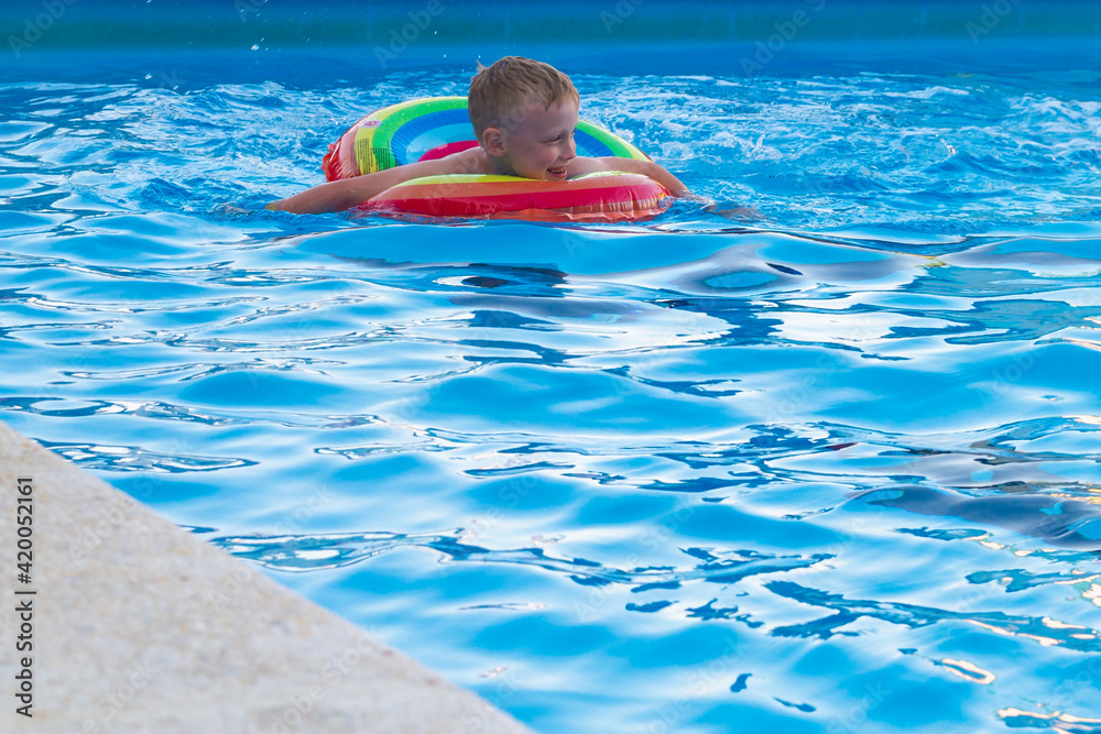 Caucasian boy swims in the summer pool on an inflatable circle