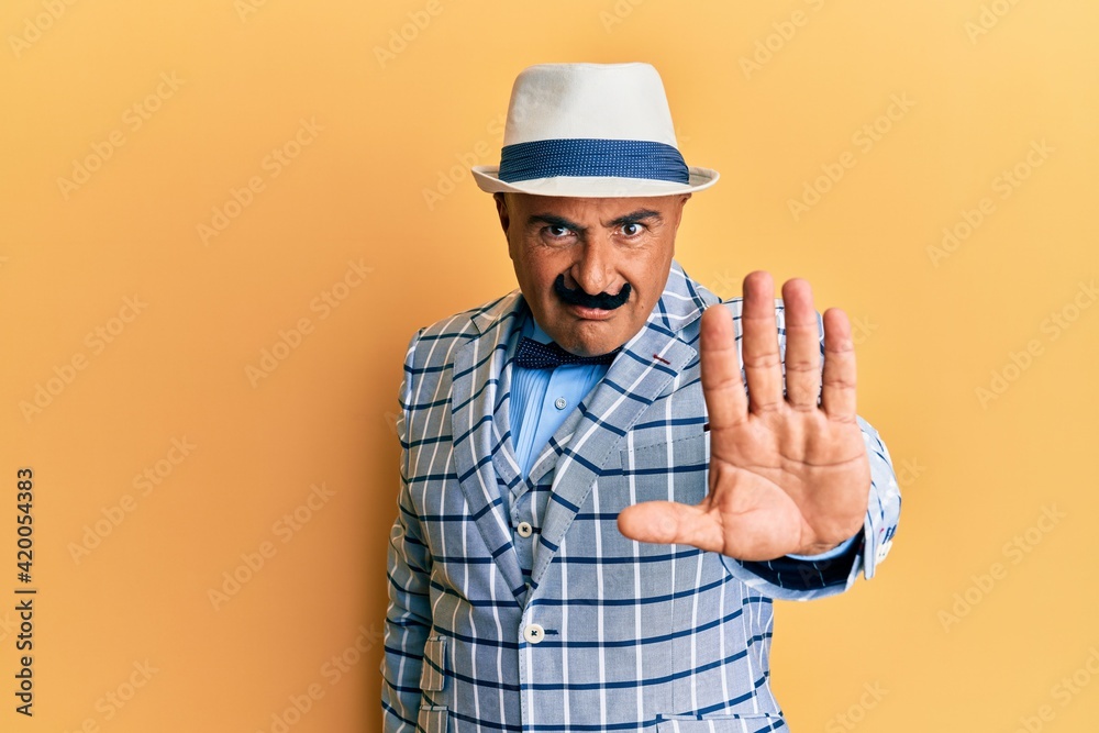 Mature middle east man with mustache wearing vintage and elegant fashion style doing stop sing with palm of the hand. warning expression with negative and serious gesture on the face.
